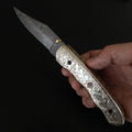 Canivete modelo artesanal com lâmina de aço damasco e cabo ornamentado.
